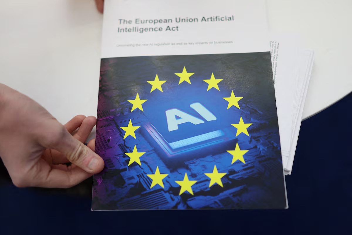 A person's hands holding a document titled 'The European Union Artificial Intelligence Act.' The cover features the EU flag stars encircling a glowing digital chip with the letters 'AI' on it, symbolizing AI regulation.