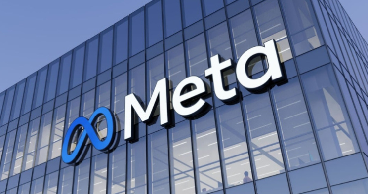 A low-angle exterior view of a modern glass office building displaying the Meta logo—the blue infinity loop symbol and the word 'Meta'—mounted prominently on the side.