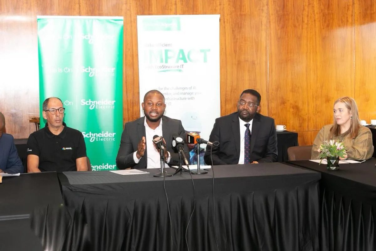 Four panelists seated at a long table during a Schneider Electric press conference, with the central speaker addressing microphones.